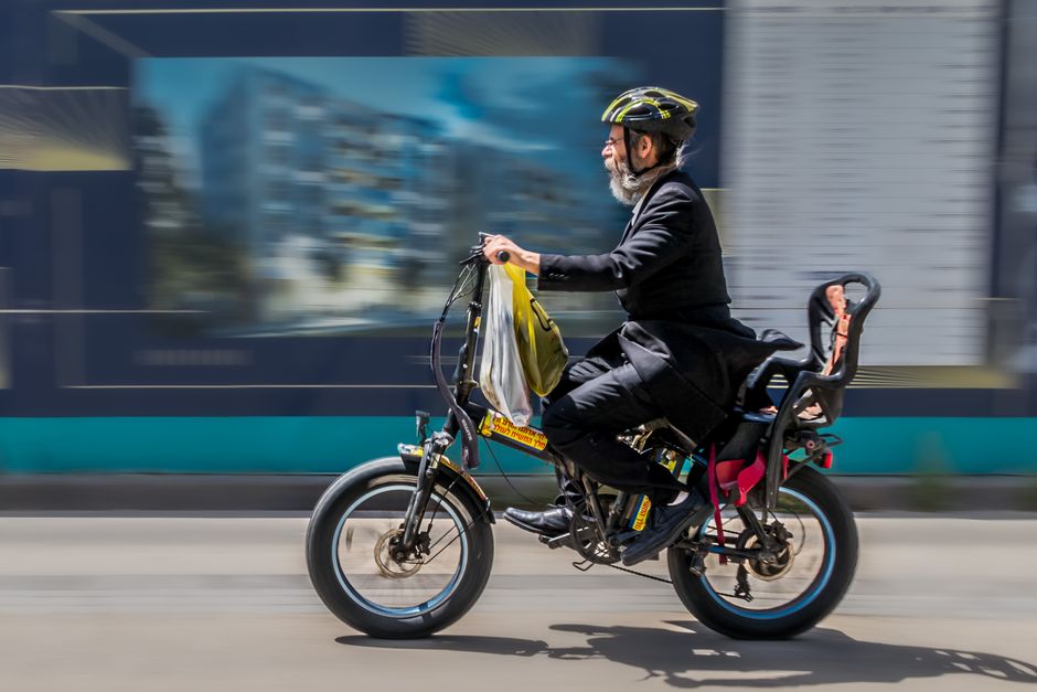 Elderly man with helmet riding an electric bicycle in motion blur. Captures urban lifestyle.