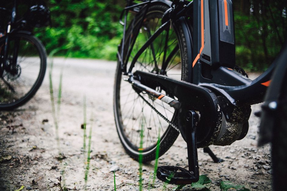 Detailed view of a mountain bike on a gravel path through lush forest foliage.