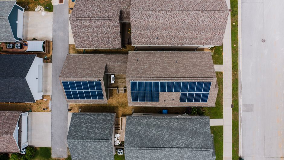 Top-down view of suburban houses featuring solar panels on roofs, showcasing renewable energy use.